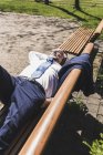 Uomo d'affari maturo sdraiato su una panchina ad ascoltare musica — Foto stock