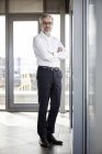 Retrato de um empresário sorridente em pé à janela — Fotografia de Stock