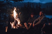 Канада, Британская Колумбия, двое мужчин, сидящих у костра у озера Бойя ночью — стоковое фото