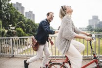 Casal feliz cruzando uma ponte com bicicleta e a pé — Fotografia de Stock