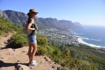 Sudáfrica, Ciudad del Cabo, mujer de pie mirando la costa durante el viaje de senderismo a Lion 's Head - foto de stock