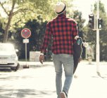 Cool young man with skateboard walking in the city, — Stock Photo