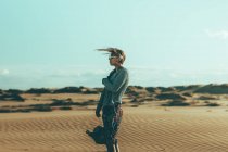Mujer joven con el pelo barrido por el viento de pie en el paisaje del desierto - foto de stock