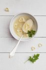 Silver spoon in bowl of chicken soup with heart-shaped noodles and parsley — Stock Photo