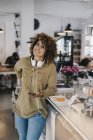 Young woman with headphones in coworking space, taking a break, eating cake — Stock Photo