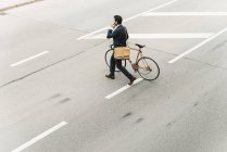 Uomo d'affari con bicicletta sul cellulare che cammina per strada — Foto stock
