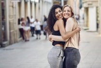 Portrait of two happy friends hugging each other on the street — Stock Photo