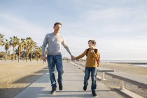 Отец и сын гуляют по пляжной набережной — стоковое фото