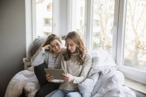 Two teenage girls using tablet at home — Stock Photo