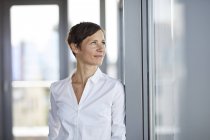 Smiling businesswoman in office looking sideways — Stock Photo