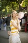 Porträt einer jungen Frau, die auf einem Streetfood-Festival rosa Zuckerwatte isst — Stockfoto