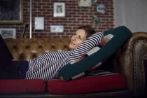 Frau entspannt sich zu Hause auf dem Sofa, träumt — Stockfoto