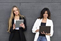 Dos empresarias usando tablet y laptop - foto de stock