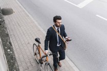 Geschäftsmann mit Fahrrad und Handy auf der Straße — Stockfoto