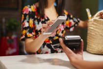 Close-up of customer paying cashless with smartphone at counter of a store — Stock Photo