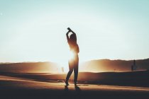 Silhouette of woman standing in desert landscape at sunset — Stock Photo