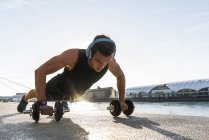 Fit athlete doing push ups at the river — Stock Photo