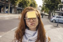 Femme rousse avec une note adhésive collant sur son front — Photo de stock