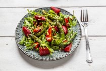 Salad of green asparagus, rocket, strawberries and pine nuts — Stock Photo