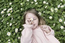 Portrait of little girl lying on flower meadow — Stock Photo