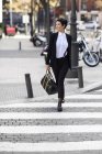 Souriant jeune femme d'affaires traversant la rue — Photo de stock