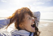 Mujer pelirroja disfrutando del aire fresco en la playa - foto de stock
