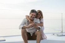 Coppia matura che guarda uno smartphone, seduta su una barca a vela — Foto stock