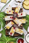Pina Colada popsicles with candied cherries and pineapple on leaves — Stock Photo