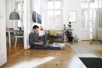 Man sitting in foor, using laptop, working from home — Stock Photo
