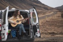 Islande, femme devant van jouant de la guitare — Photo de stock