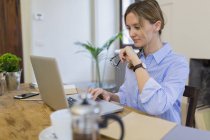 Woman using laptop on wooden desk at home — Stock Photo