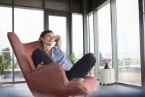 Woman sitting in armchair at home relaxing — Stock Photo