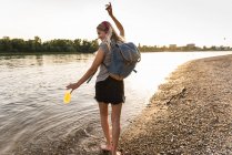 Jeune femme marchant pieds nus sur la rivière, écouteurs et smartphone — Photo de stock