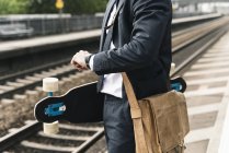 Primo piano di uomo d'affari con skateboard in attesa alla piattaforma — Foto stock