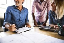 Colegas felizes com plano na mesa no escritório — Fotografia de Stock