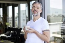Человек, стоящий у французов и наслаждающийся чашкой кофе — стоковое фото