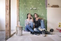 Couple renovating new house, sitting on ground planning bathroom — Stock Photo