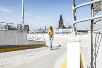 Германия, Кельн, женщина, идущая по пандусу уровня paking с помощью мобильного телефона — стоковое фото