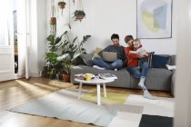 Familie sitzt auf Couch und benutzt Laptop — Stockfoto