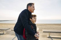 Padre e figlio con scooter sul lungomare al tramonto — Foto stock