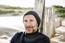 Portrait d'un homme souriant à la clôture sur la plage — Photo de stock