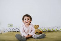 Ritratto di bambina felice seduta sul letto — Foto stock