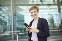 Portrait of blond businesswoman using smartphone — Stock Photo