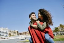 Happy young man giving girlfriend a piggyback ride — Stock Photo