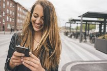 Happy young woman using cell phone in the city — Stock Photo