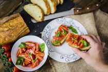 Taking bruschetta, white bread with tomato and olive oil — Stock Photo