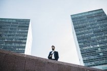 Homme d'affaires debout devant les tours de bureaux — Photo de stock