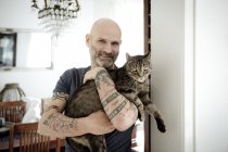 Tattooed man carrying his cat — Stock Photo