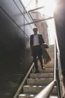 Maduro hombre de negocios caminando por las escaleras de la ciudad - foto de stock