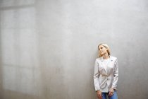 Donna d'affari rilassata in piedi di fronte al muro grigio — Foto stock
